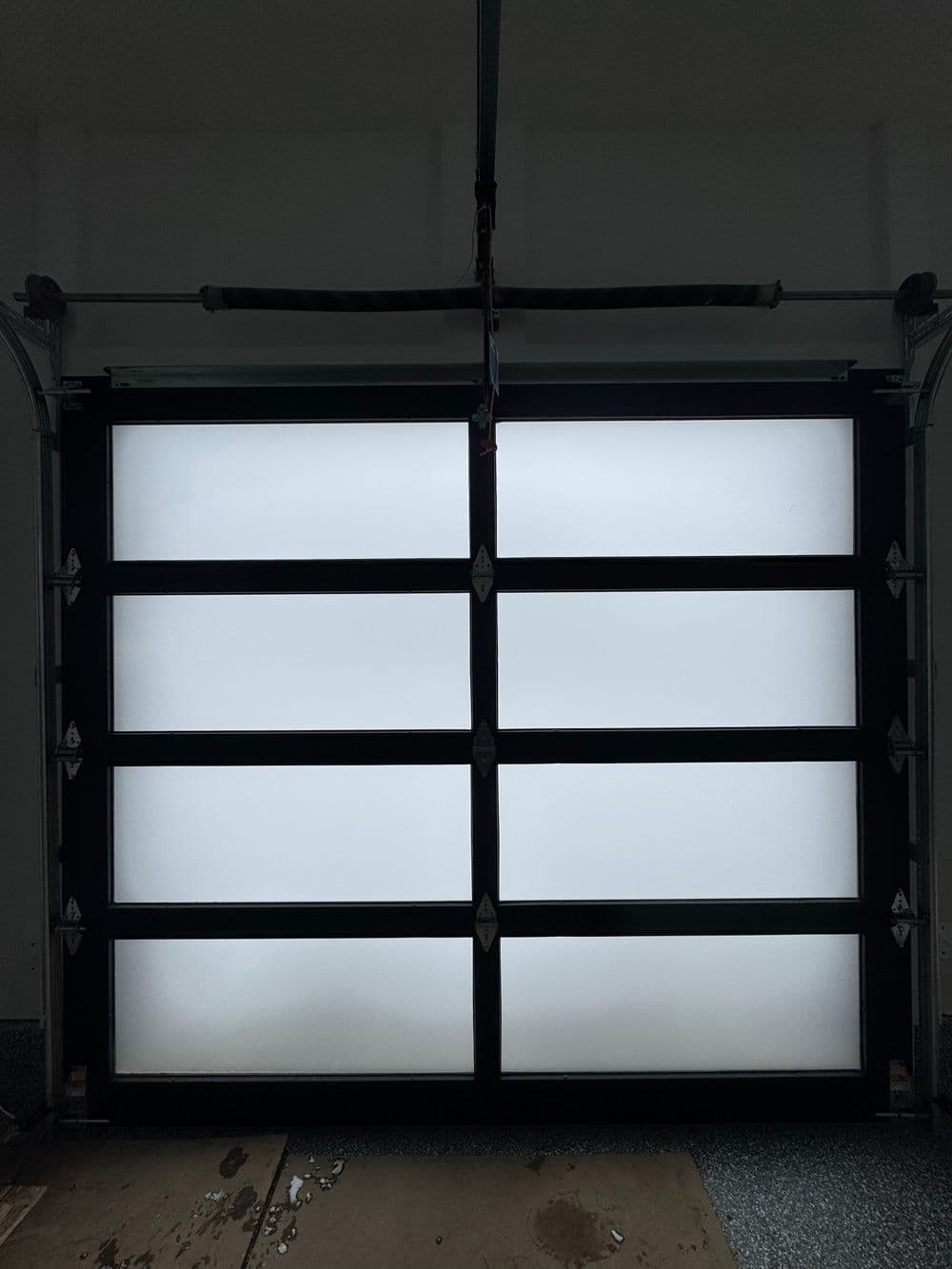 Modern black garage door with frosted panels, showcasing a sleek design and contemporary style.