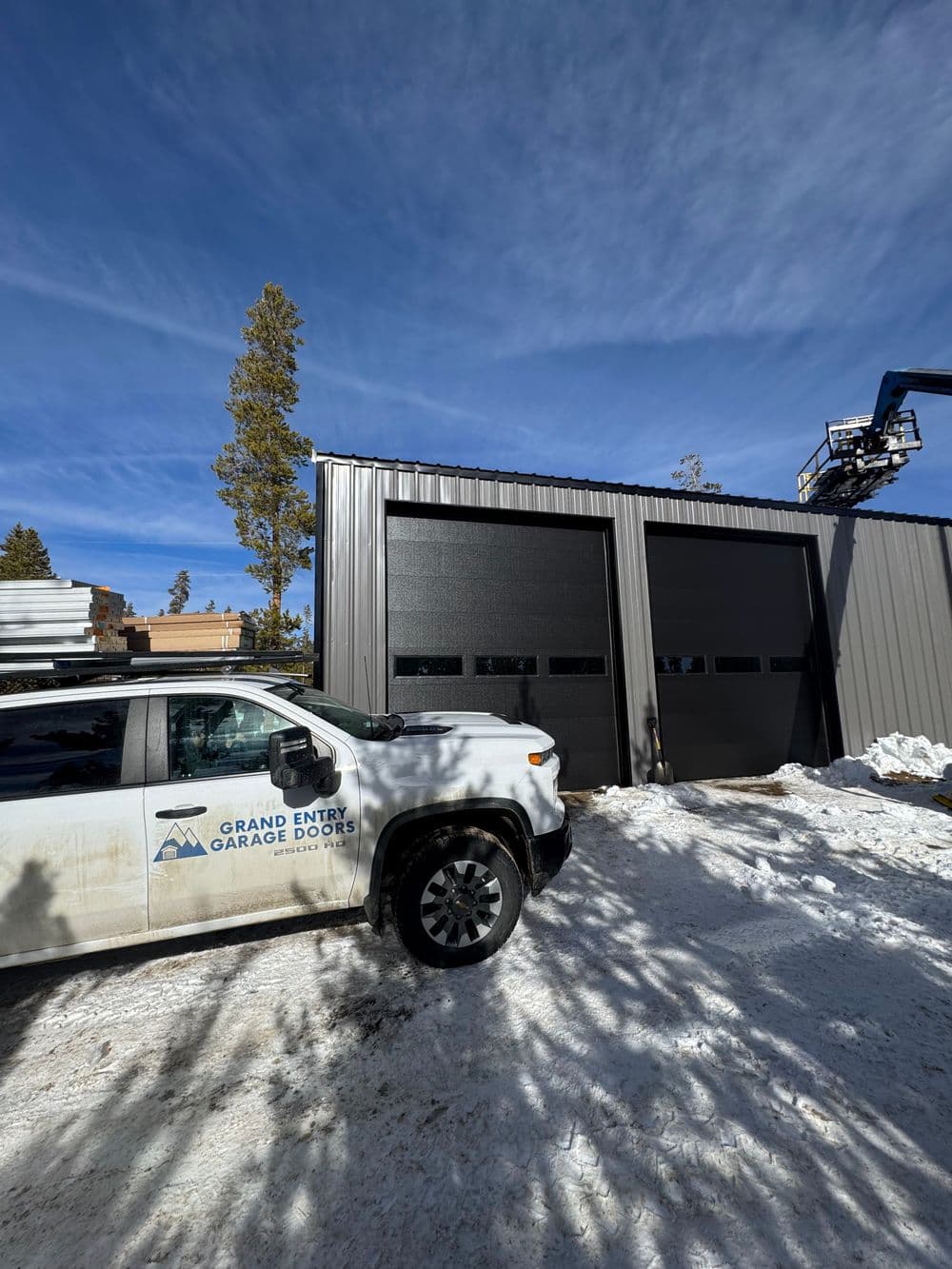 Garage door installation in snowy environment with a company vehicle outside.
