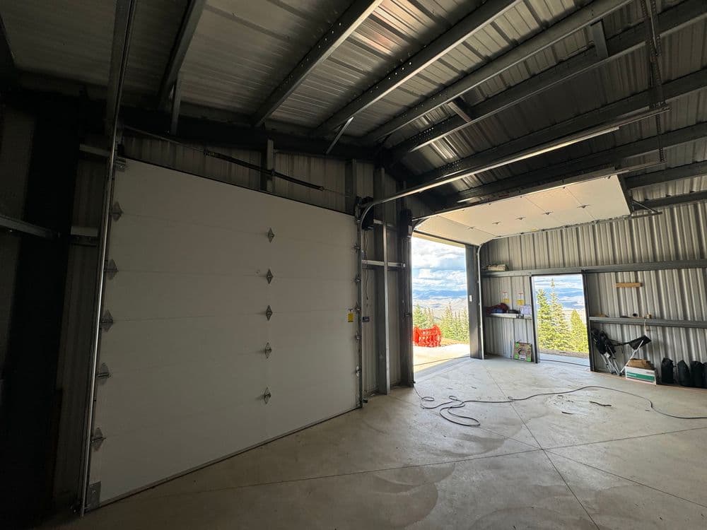 Spacious garage interior with large roll-up door and scenic outdoor view.