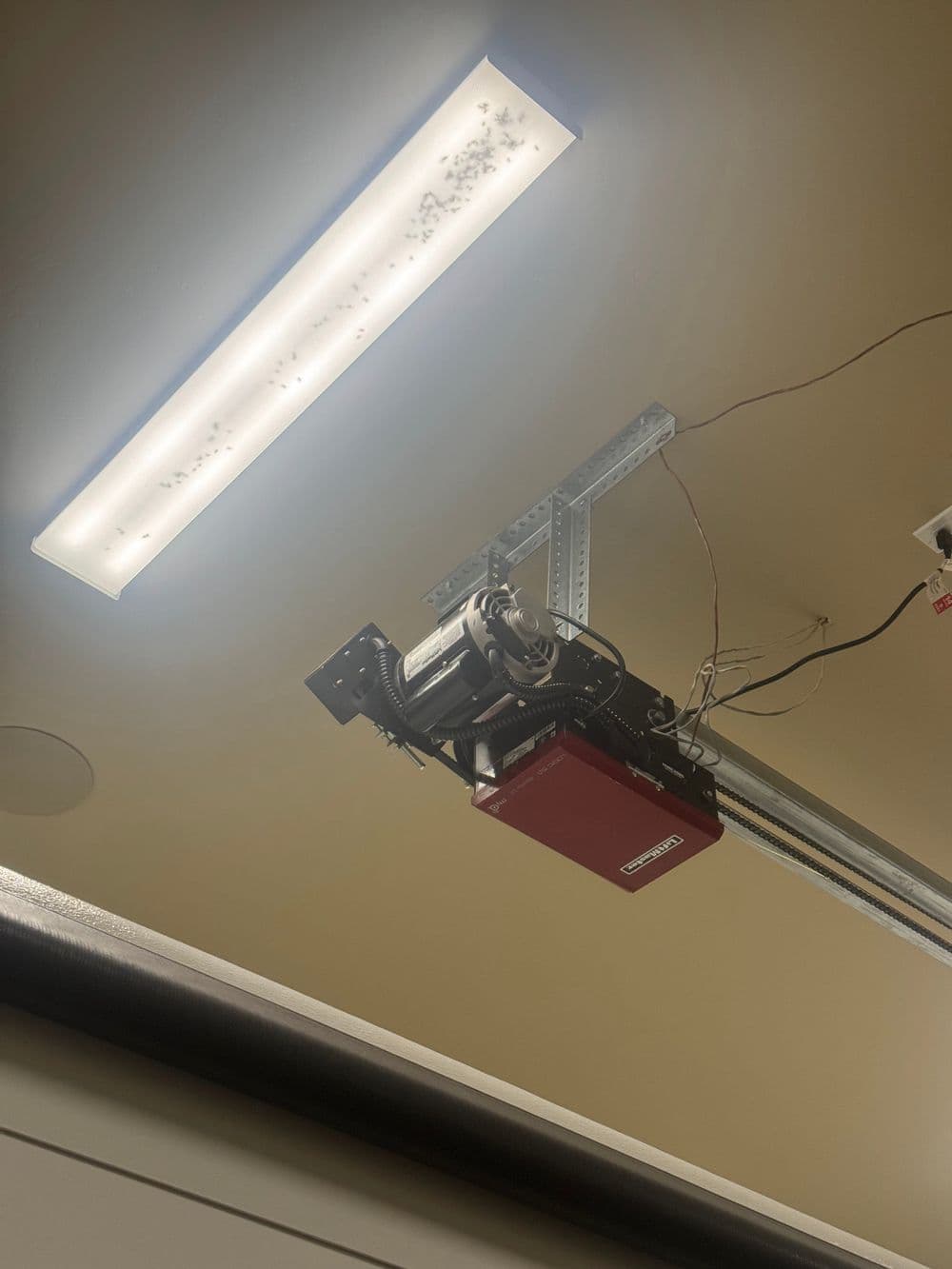 Garage door opener mounted on ceiling with overhead LED light fixture.