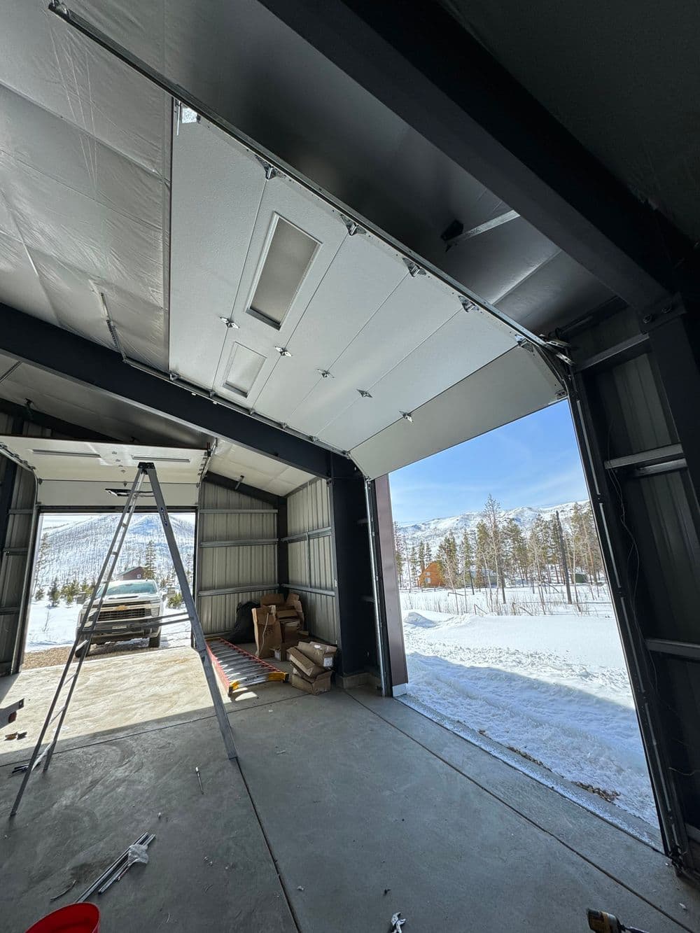 Interior of a garage with wide open doors, snow-covered landscape visible outside.