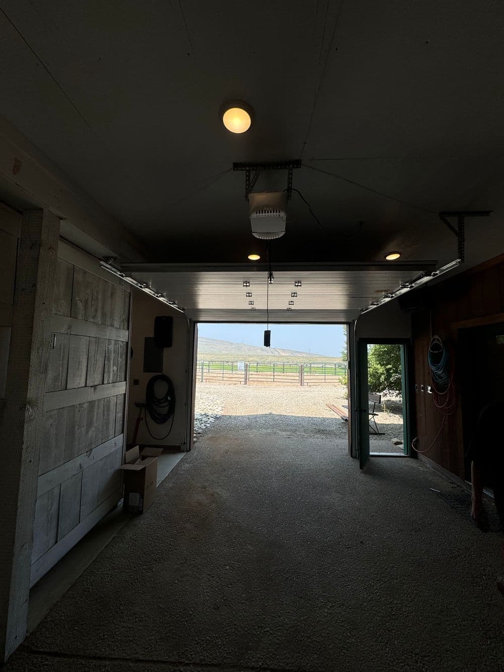 Interior view of a spacious garage with open door, natural light, and outdoor scenery.