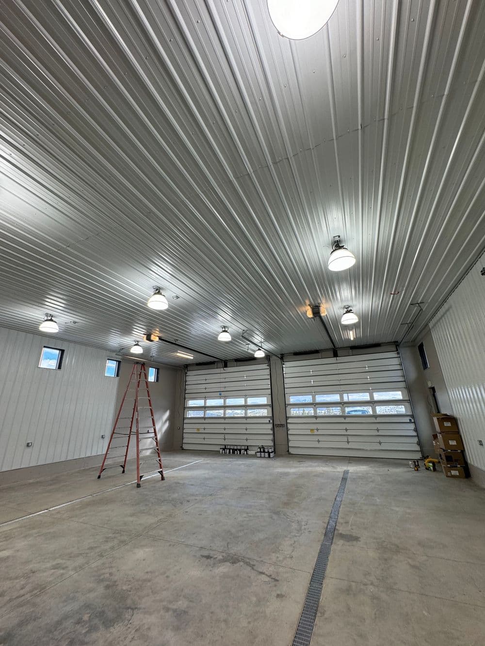Spacious commercial garage interior with bright lighting and a tall ladder.