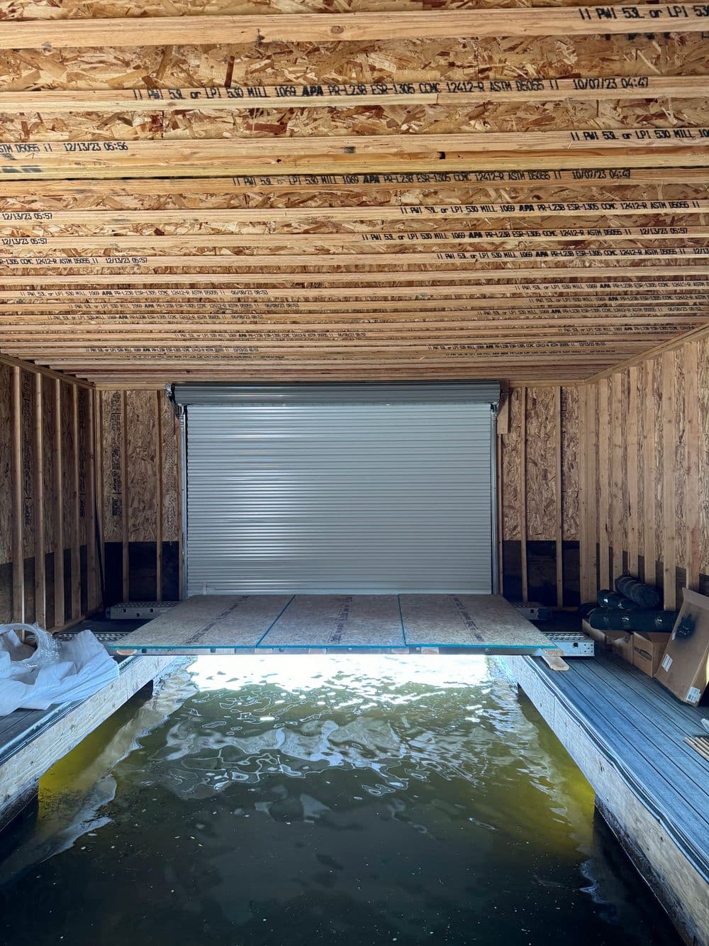 Interior view of a partially constructed garage with a water dock and roller door.