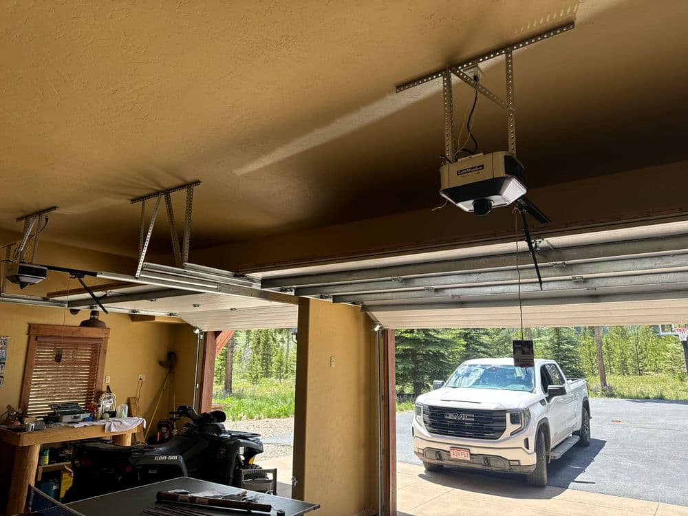 Garage interior with ceiling mounted garage door opener and a truck parked outside.