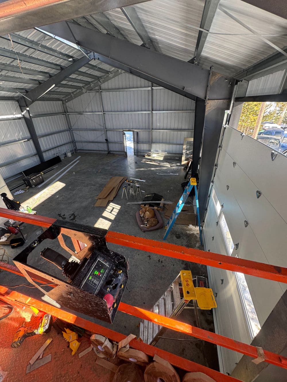 Interior view of a spacious industrial warehouse under construction with tools and materials visible.