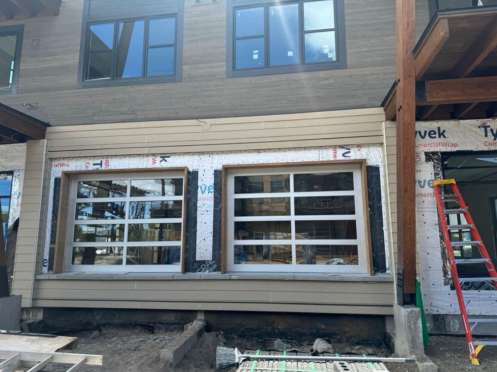 Newly installed windows on modern home exterior with construction materials and ladder.