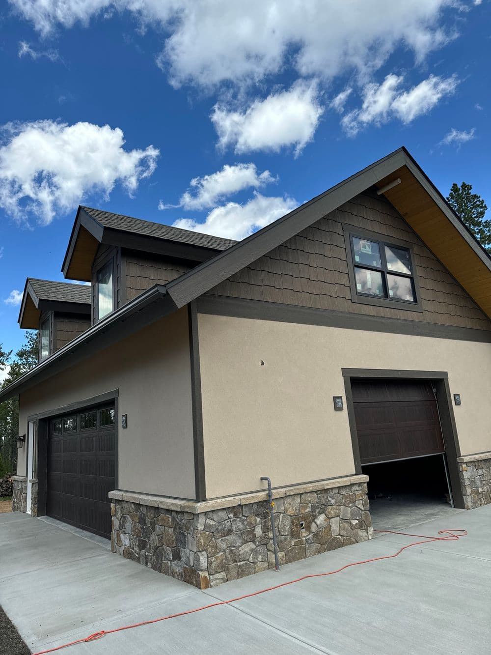 Modern two-story house with stone accents and a clear blue sky backdrop.