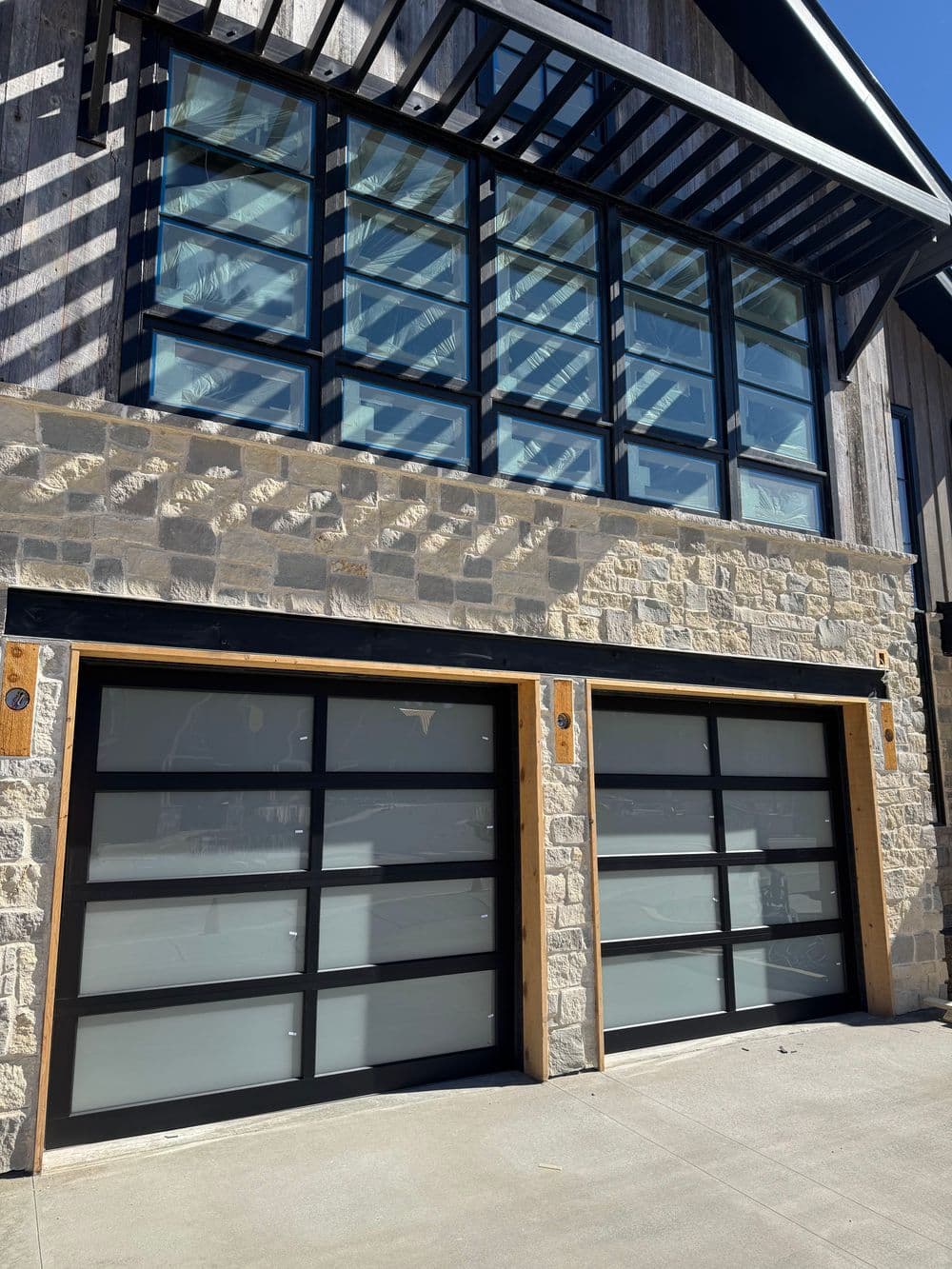 Modern garage doors with frosted glass panels below a stylish wooden building facade.