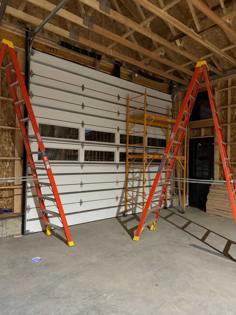 Red ladders and scaffolding in a garage under construction, showcasing unfinished interior.