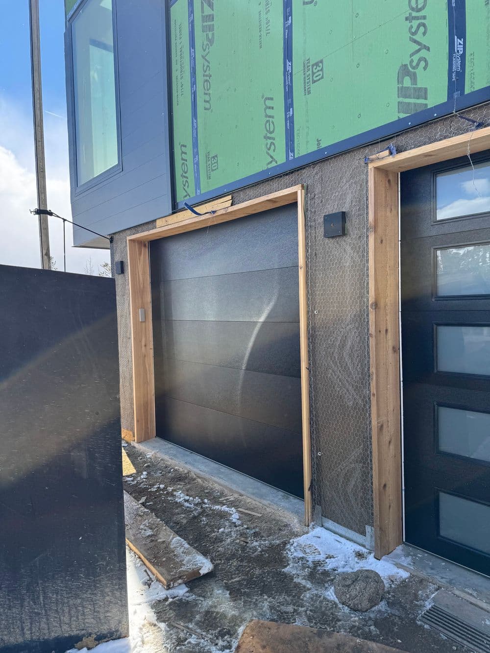 Modern garage doors in a home construction site with insulation materials visible.