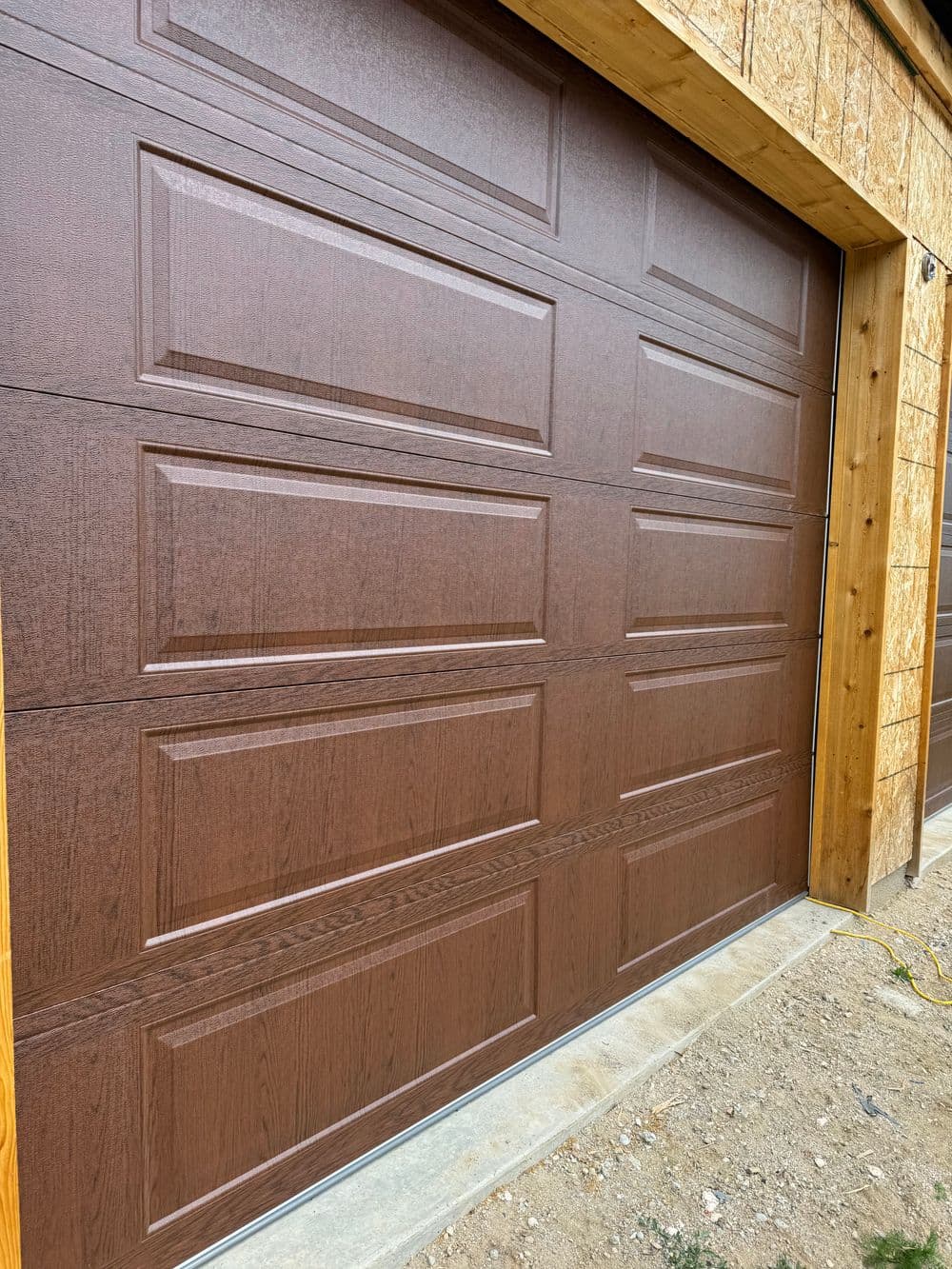 Brown wooden texture garage door with panel design, installed in a residential building.