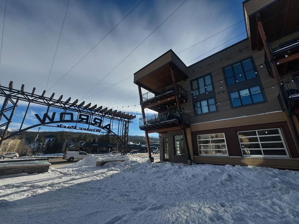 Winter scene of a modern building near a welcoming sign in snowy landscape.