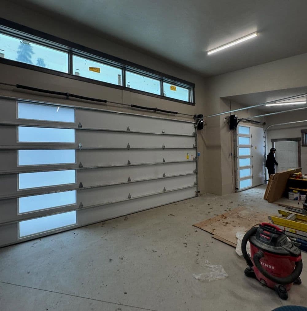 Interior view of a spacious garage with two large garage doors and construction materials present.