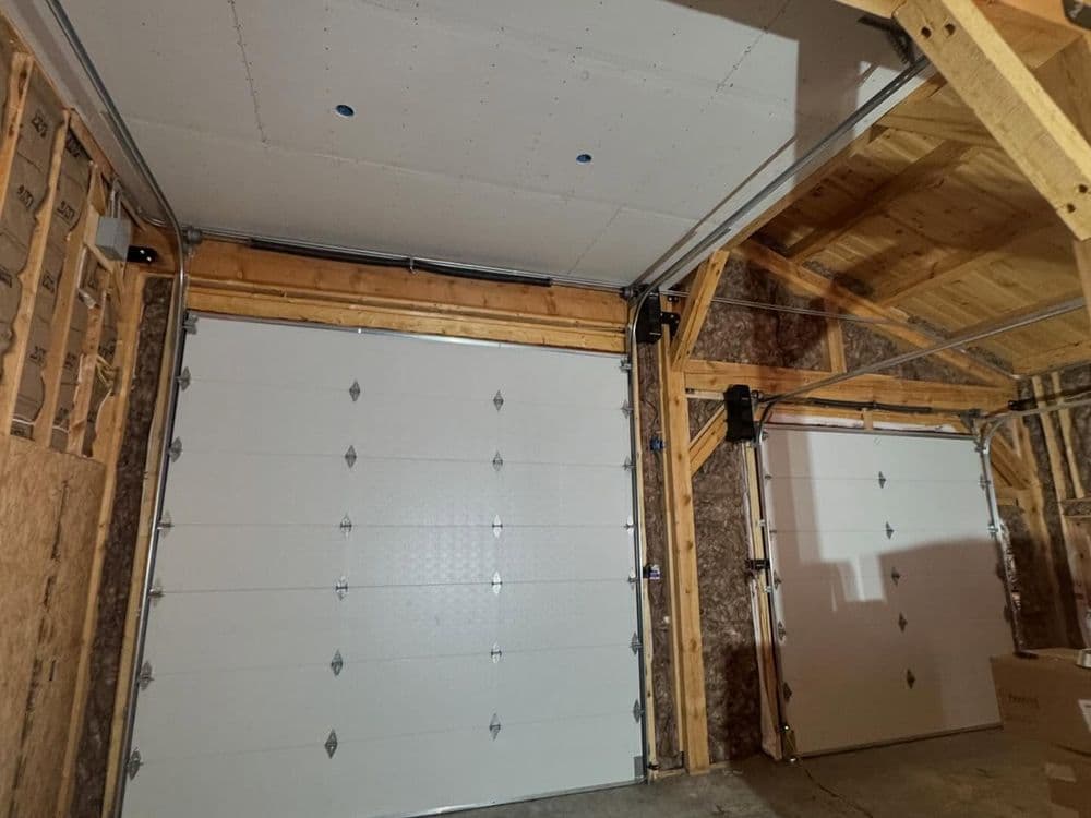 Interior view of a spacious garage featuring dual garage doors and wooden framing.